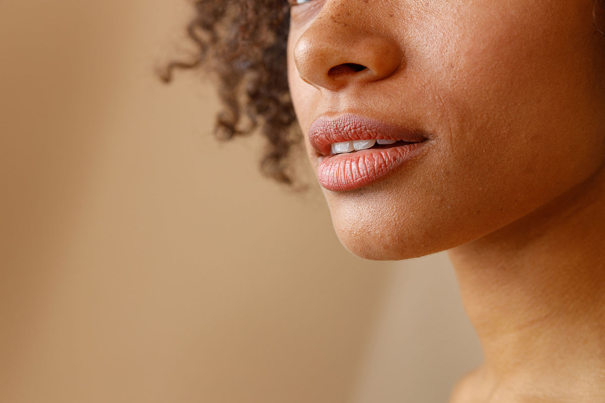 Close-up of a woman's lower face with full, natural lips and smooth skin