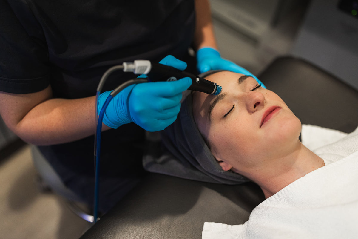 Gloved practitioner guiding a HydraFacial handpiece along a patient's forehead at Element Dermatology