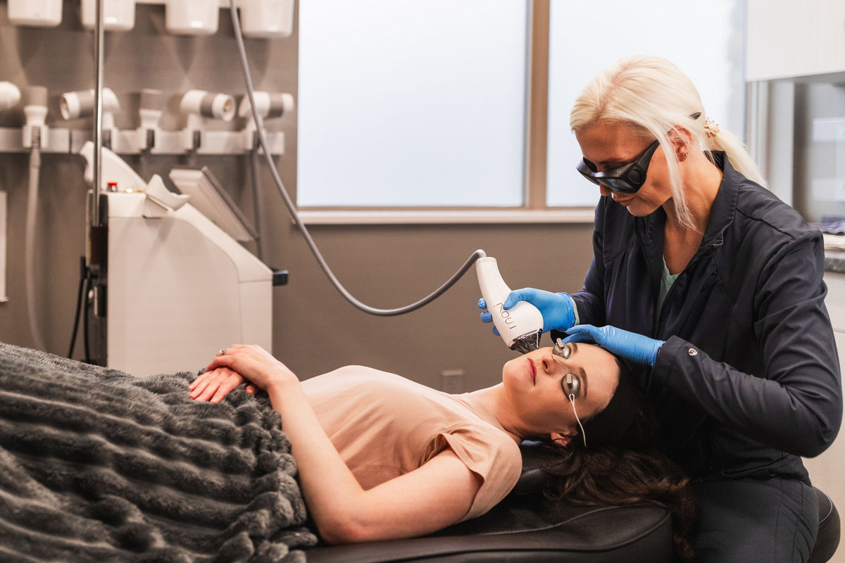 Clinician in protective goggles applying a laser handpiece to a patient's forehead at Element Dermatology