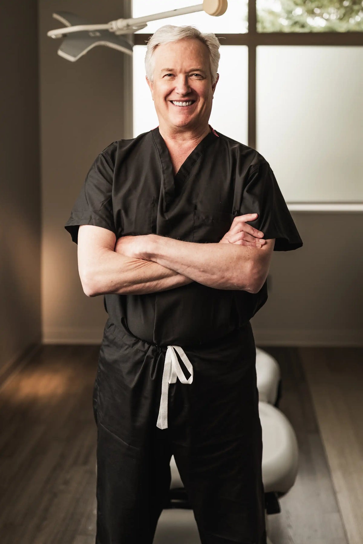 Dr. Barry LaBine, dermatologist at Element Dermatology, in black scrubs with arms crossed
