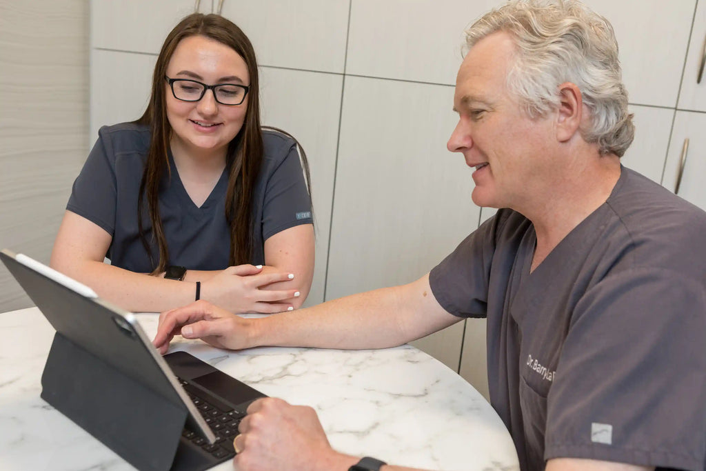 Two clinicians in scrubs reviewing information on a tablet at Element Dermatology