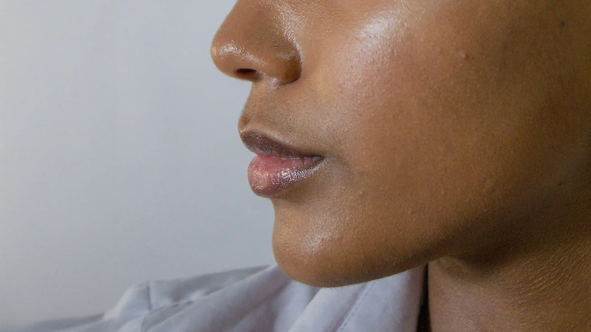 Close-up side profile of a face with deep brown skin, showing the nose and lips