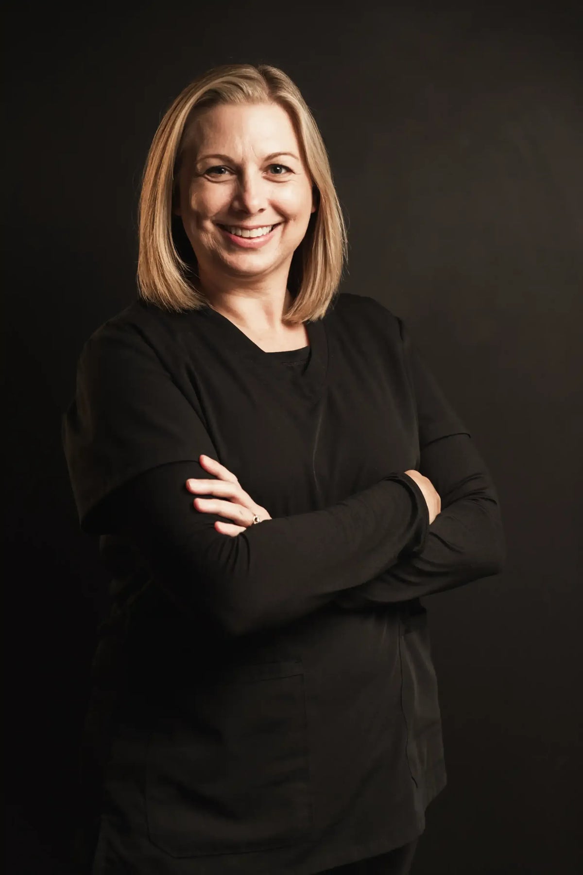 Kristin, Element Dermatology team member, with a blonde bob in a black top, smiling