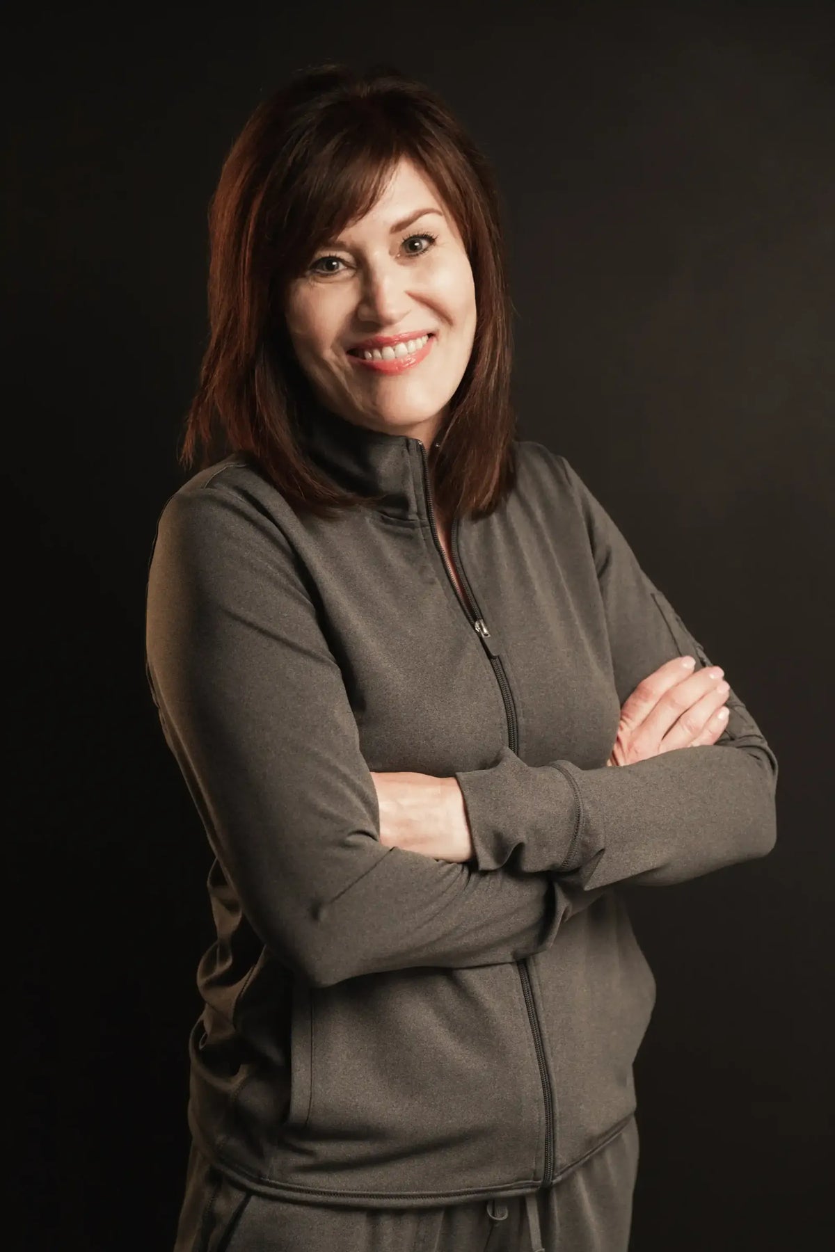 Leslie, Element Dermatology team member, with auburn hair in a grey jacket, smiling