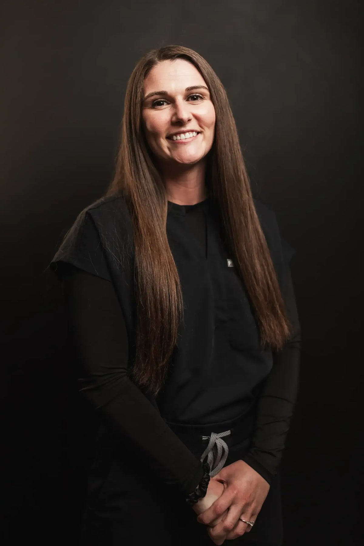 Shawnee, Element Dermatology team member, with long brown hair in black scrubs