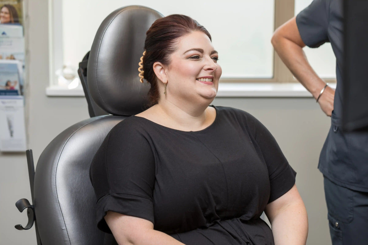 Smiling patient in a treatment chair consulting with a provider at Element Dermatology