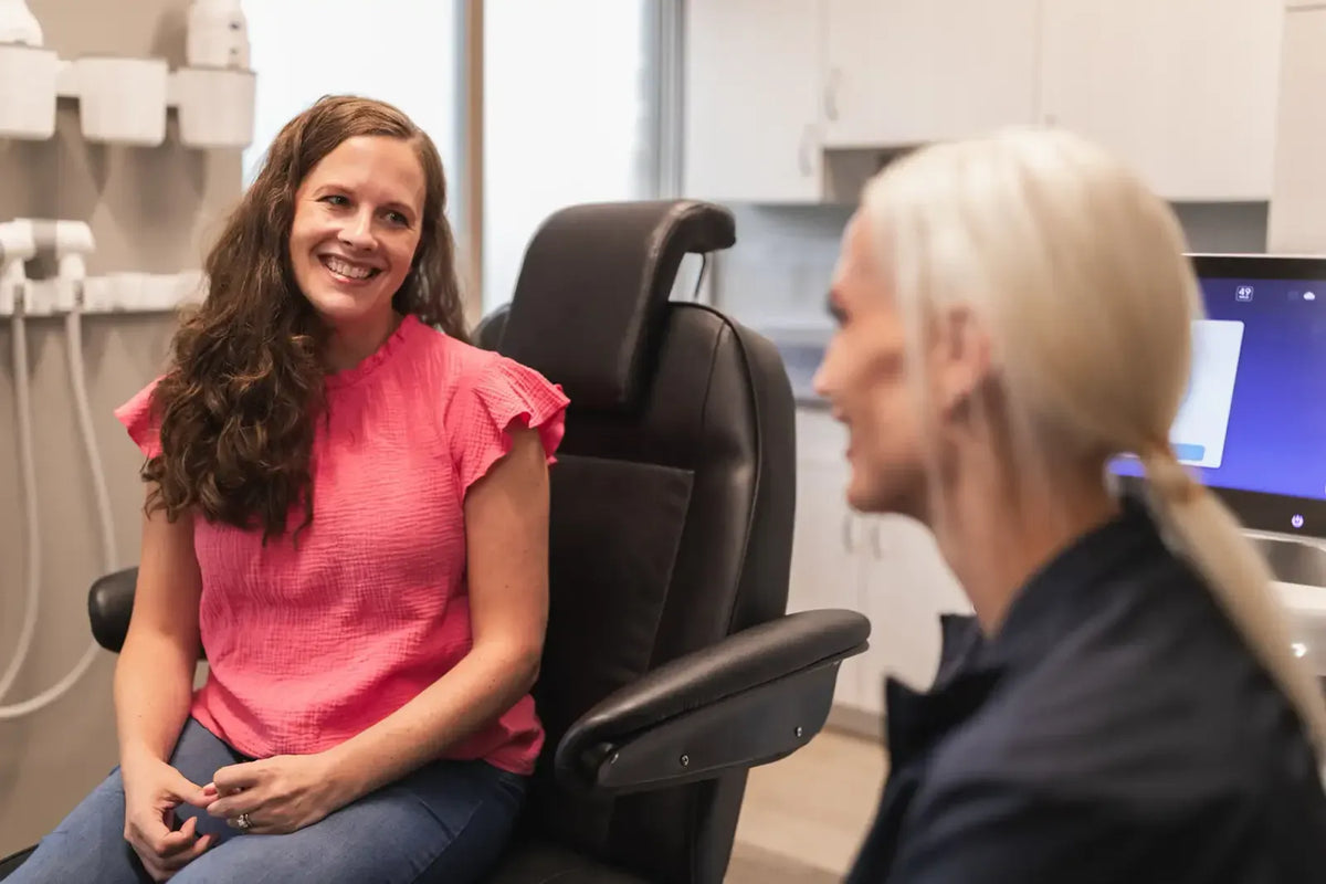 Patient in a pink top smiling during a consultation with a provider at Element Dermatology