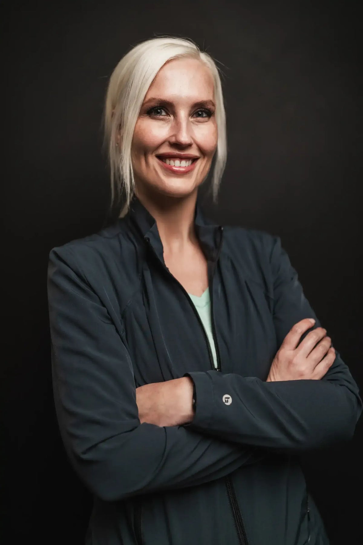 Tammy, Element Dermatology team member, with a platinum blonde bob in a dark jacket
